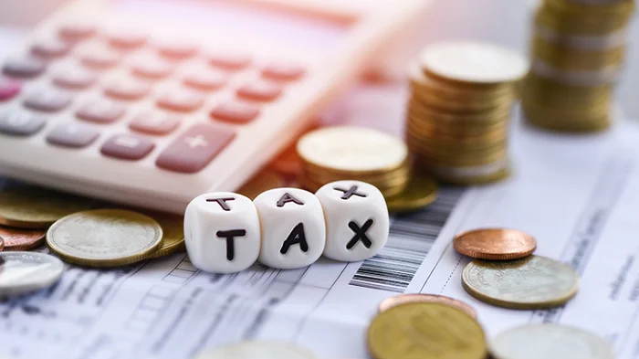 Máy tính, tiền xu và các khối chữ TAX trên tài liệu tài chính