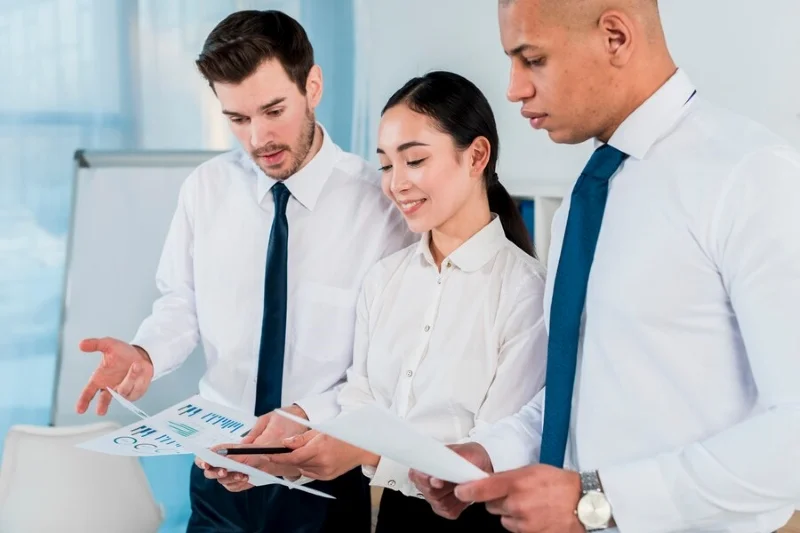 Ba nhân viên cùng xem và thảo luận báo cáo tài chính