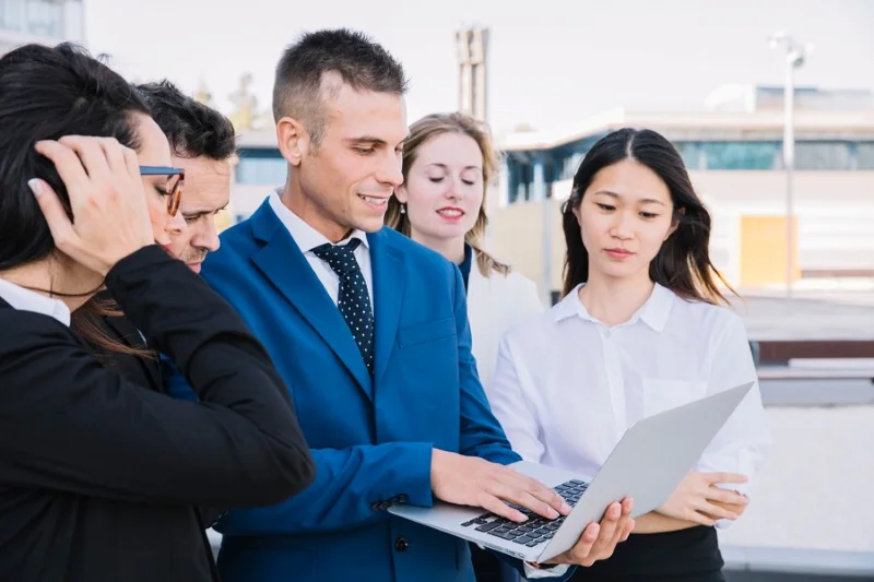 Nhóm người mặc trang phục công sở cùng xem máy tính xách tay.