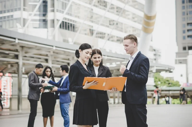 Nhóm người trao đổi công việc và xem hồ sơ bên ngoài tòa nhà.