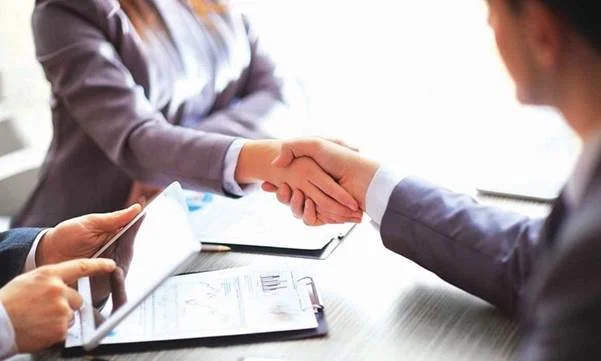 Hai người bắt tay trên bàn có tài liệu