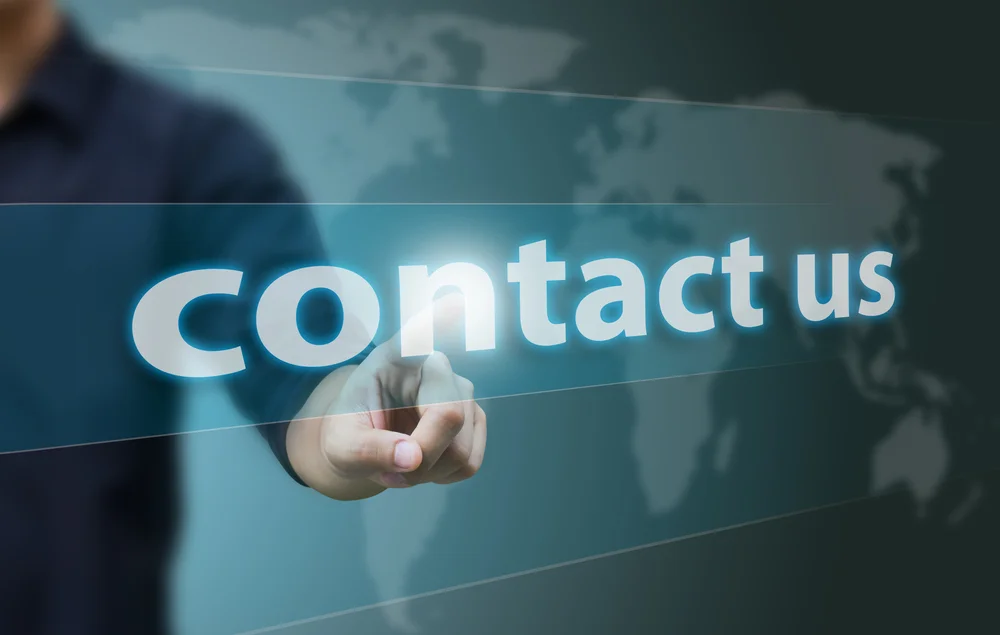 Bàn tay chạm vào dòng chữ Contact us trên màn hình minh họa.